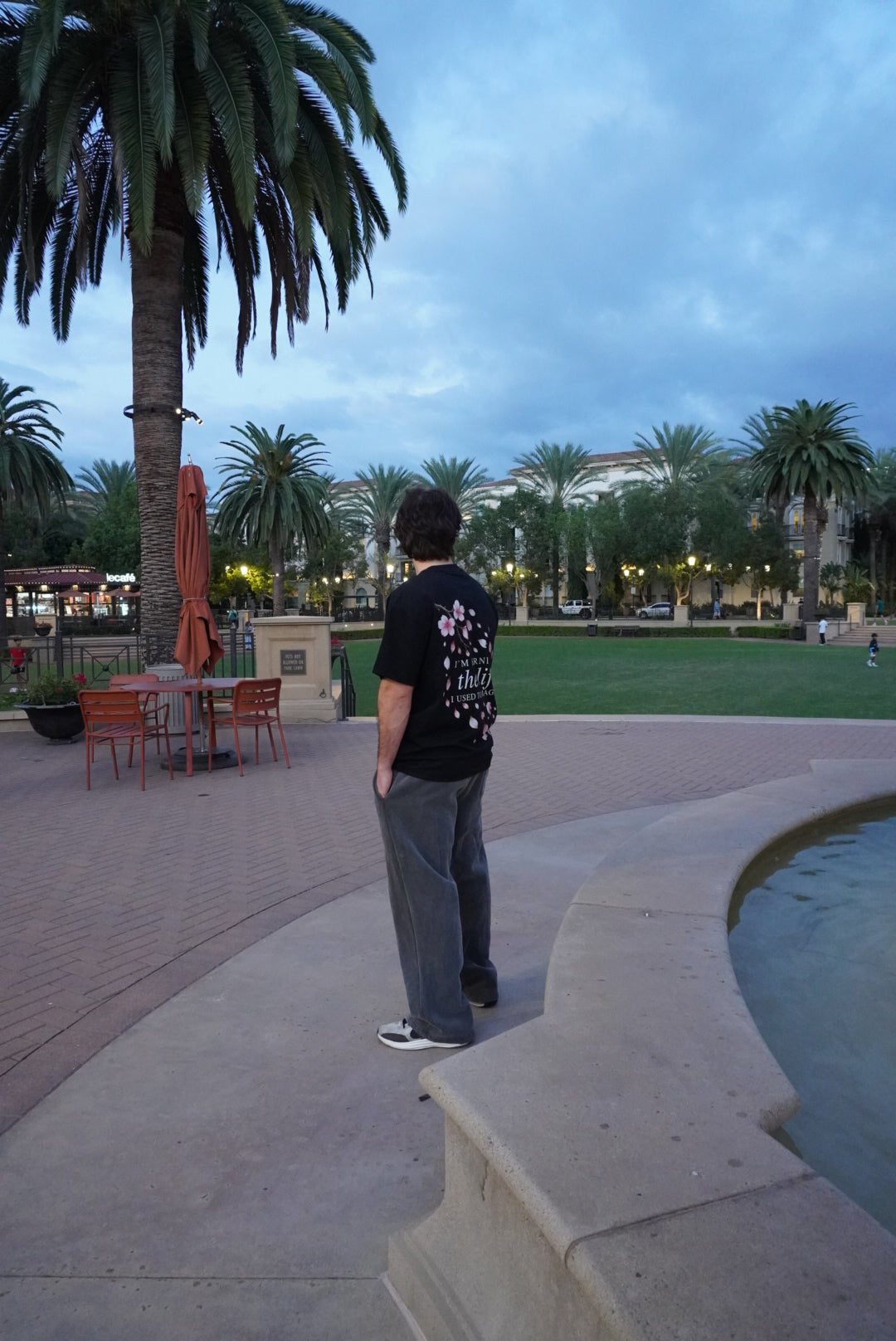 Cherry Blossom graphic tee worn beside a fountain at dusk